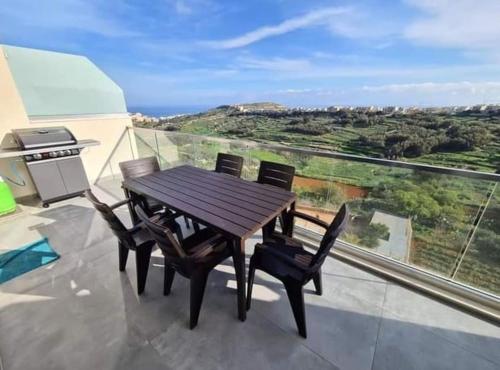 a wooden table and chairs on a balcony with a grill at Lovely home with beautiful view with communal pool by 360 Estates in Taʼ Bullara