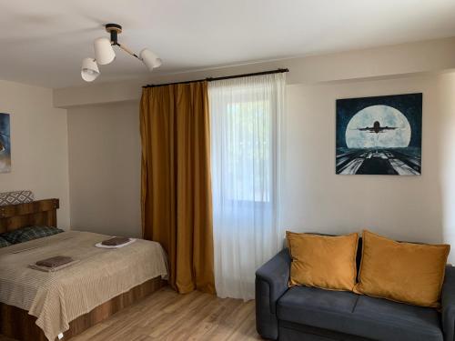 a bedroom with a bed and a couch and a window at AVIATOR Apartments in Bakuriani in Bakuriani