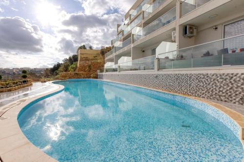 a large swimming pool in front of a building at Lovely home with beautiful view with communal pool by 360 Estates in Taʼ Bullara