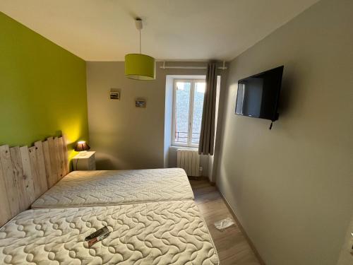 - une chambre avec un lit et une télévision murale dans l'établissement Le Sancy nectaire, à Saint-Nectaire