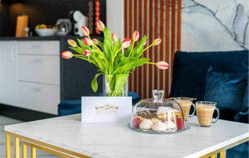 a table with a vase with pink tulips in it at 2 Bedroom Cozy Home In Sarbinowo in Sarbinowo