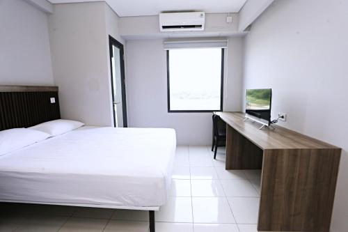 a bedroom with a bed and a desk and a window at Nusantara Rooms Riverdale By Reccoma in Cikarang