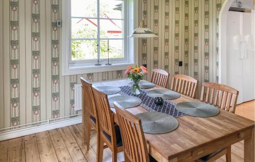 a wooden table with chairs and a vase of flowers at 4 Bedroom Beautiful Home In Mönsterås in Mönsterås