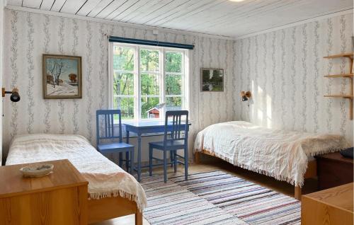 a bedroom with two beds and a table and a window at 3 Bedroom Lovely Home In Högsby in Högsby