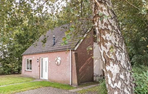 a small brick house with a white door next to a tree at Nice Home In Hoeven With Sauna in Hoeven