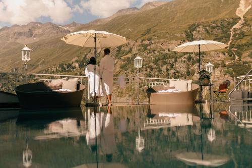 two people standing on a boat with umbrellas in the water at Gourmet & Wine Hotel Austria - 4 Sterne superior - Ski In Ski Out in Obergurgl