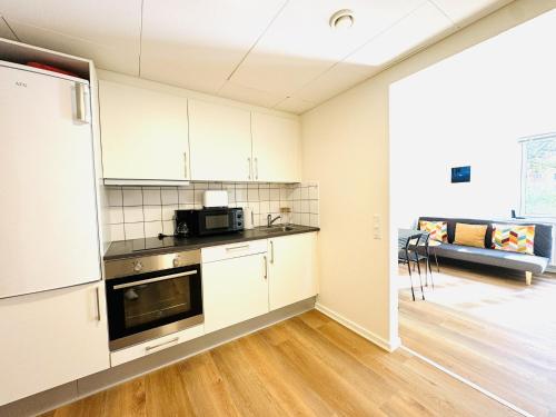 a kitchen with white cabinets and a microwave at aday - Charming and Bright Studio Apartment in Aalborg