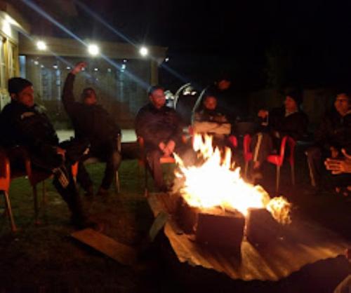a group of people sitting around a fire pit at Hargisa Hut in Skardu