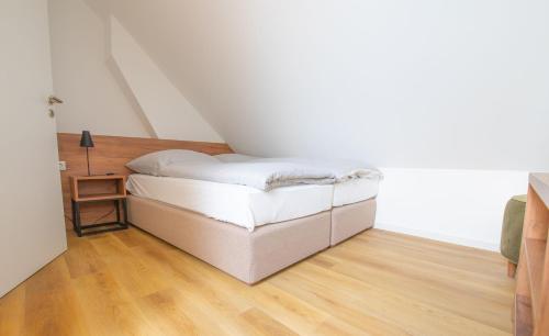 a small white bed in a room with a wooden floor at Küstenblick in Carolinensiel
