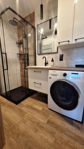 y baño con ducha y lavadora. en Magmares Apartment, en Bydgoszcz