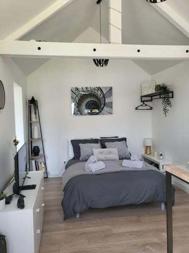 une chambre avec un grand lit dans une pièce blanche dans l'établissement Agréable studio avec cour à 10mn de Fontainebleau, à Héricy