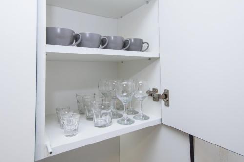 a cupboard with wine glasses and plates on it at CityApartments Kyiv Obolon in Kyiv