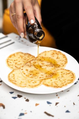 a person pouring syrup on a plate of pancakes at Graphik Montparnasse in Paris