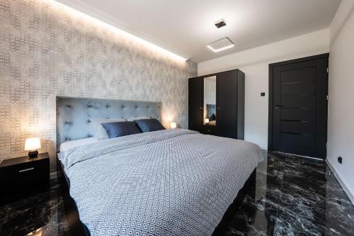 a bedroom with a large bed with a blue headboard at Black Luxury Apartment in Janów