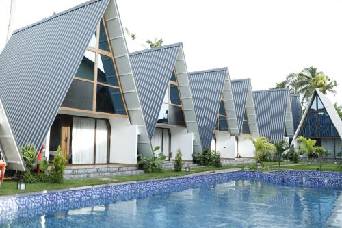 un bâtiment avec une piscine devant dans l'établissement Leela's 7th Heaven Resort & Spa, à Turcunapulli