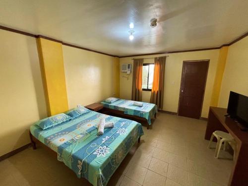 a hotel room with two beds and a television at White Beach Hotel Puerto Galera powered by Cocotel in Puerto Galera