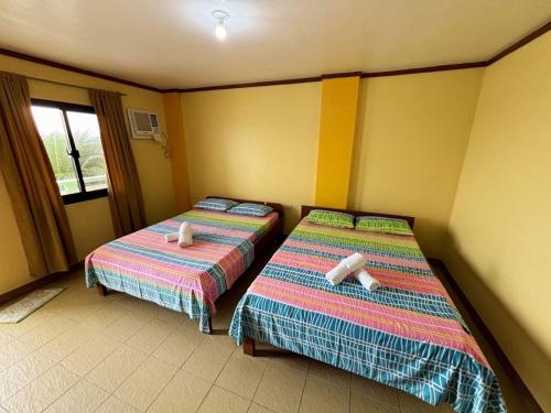 two beds sitting next to each other in a room at White Beach Hotel Puerto Galera powered by Cocotel in Puerto Galera