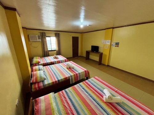 a hotel room with two beds and a television at White Beach Hotel Puerto Galera powered by Cocotel in Puerto Galera