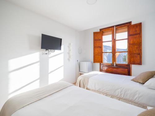 two beds in a room with a window and a tv at Texeda Room Suites in Tejeda