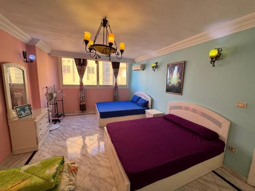 a bedroom with two beds and a chandelier at شقه بغرفتي نوم فيو بحر كامل إسكندرية in Alexandria