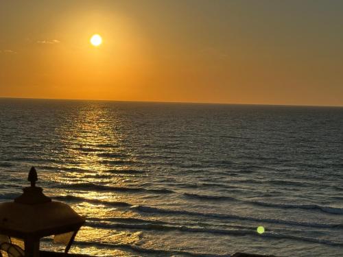 a sunset over the ocean with a beach umbrella at شقه بغرفتي نوم فيو بحر كامل إسكندرية in Alexandria