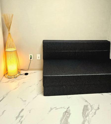 a bed with a black mattress and a lamp at Majestic Seoul Stay Central in Seoul