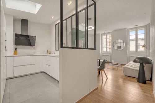 une cuisine avec des armoires blanches et un salon dans l'établissement Madinina - Appt de 72 m² à Toulouse, à Toulouse