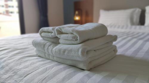 four towels stacked on top of a bed at The European Chiang Mai in Chiang Mai
