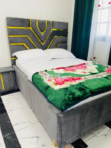 a bed with a green blanket with roses on it at Residence SVET in Kribi