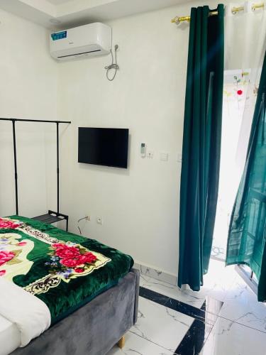 a bedroom with a bed and a television on the wall at Residence SVET in Kribi