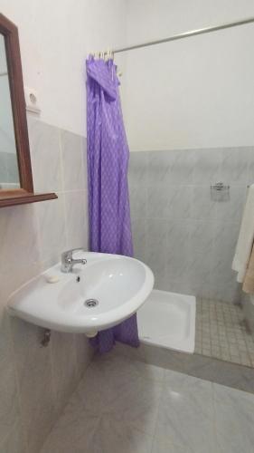 a bathroom with a sink and a purple shower curtain at Pensão Alcinda Bettencourt 100 meters to the Beachfront in Santa Maria