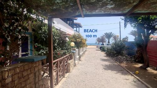 a sidewalk next to a beach sign on a building at Pensão Alcinda Bettencourt 100 meters to the Beachfront in Santa Maria