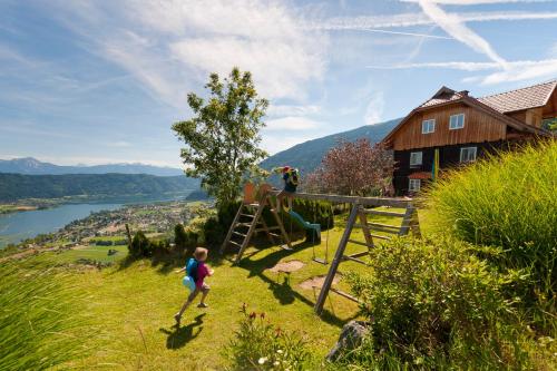 a little girl running on a hill near a house at Blaues Haus Ferienwohnung Bodensdorf Ossiacher See Gerlitzen Alpe in Bodensdorf