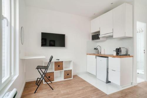 - une cuisine avec des placards blancs et une chaise dans l'établissement Charmant studio cosy à Créteil, à Créteil