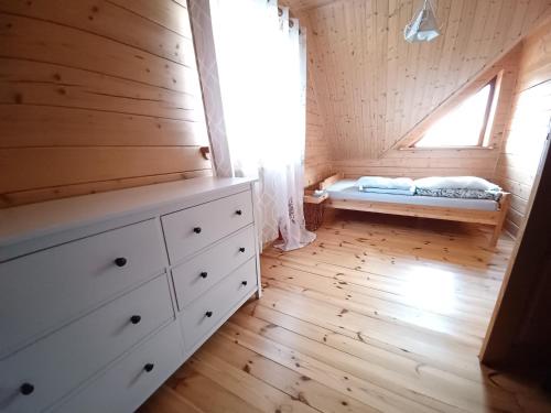 a bedroom with a bed and a window at Domki Mazury MAX in Rybical