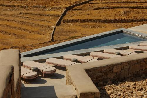 a swimming pool with a bunch of lounge chairs next to it at Sun Aeriko in Tinos Town