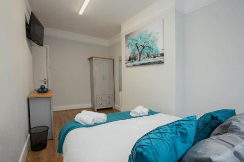 a bedroom with a white bed with blue sheets at Large Stylish 2bedroom flat in Wood Green in London