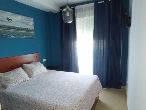 a bedroom with a bed with blue walls and a window at Mirador de los Navegantes in Sanlúcar de Barrameda