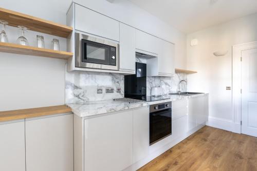 a white kitchen with white cabinets and a microwave at Hillside Luxury Apartments in Inverness