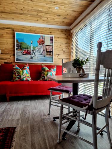 a living room with a red couch and a table at Winterton Country Lodge @ Rose Cottage in Winterton