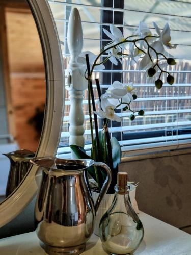 a mirror and a vase with flowers on a table at Winterton Country Lodge @ Rose Cottage in Winterton