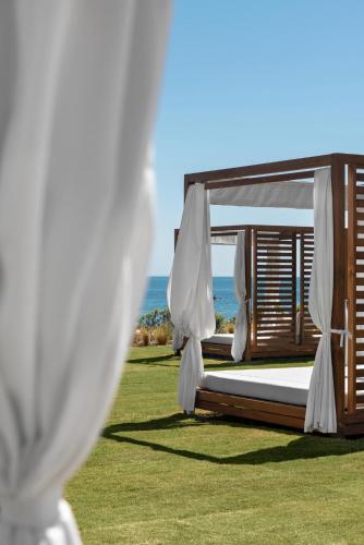 a bed in a field with the ocean in the background at Ikos Andalusia in Estepona