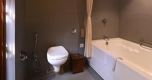 a bathroom with a toilet and a bath tub at The Golkonda Resort and Spa in Hyderabad
