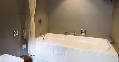 a white bath tub in a bathroom with a shower at The Golkonda Resort and Spa in Hyderabad