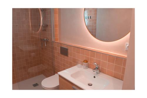 a bathroom with a sink and a toilet and a mirror at Le Petit Cathare, Nid rénové au cœur de Quillan in Quillan