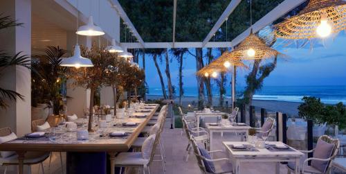 a dining room with tables and chairs and the ocean at Ikos Andalusia in Estepona