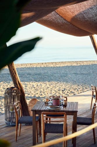 a table and chairs on a beach with the ocean at Ikos Andalusia in Estepona