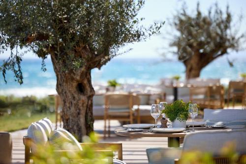 a table with wine glasses and a tree on a deck at Ikos Andalusia in Estepona