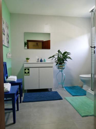 a bathroom with a sink and a toilet and blue rugs at Tea House Gerês - T1 Hipericão in Geres