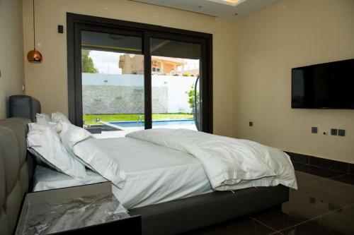 a bedroom with a bed and a large window at Villa Palm évasion in Ngaparou